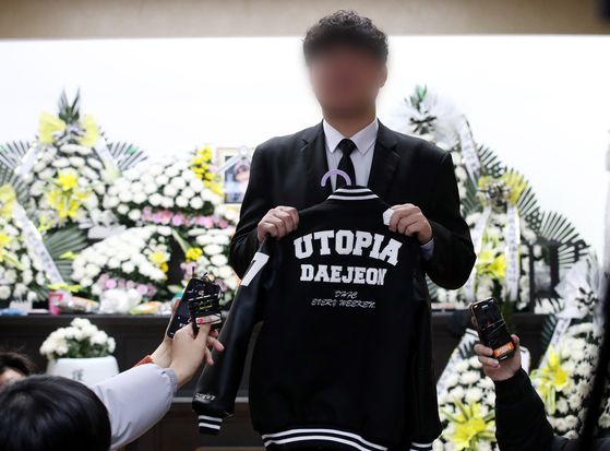 대전 초등학생 김하늘 양 피살사건이 발생한 대전 서구의 한 초등학교 정문에서 12일 오전 학교 관계자가 추모객들이 놓고 간 꽃과 편지 위에 우산을 씌워주고 있다. 학교 정문에는 시민들이 붙여놓은 쪽지와 꽃, 인형, 선물들이 가득 차 있는 모습이다. 연합뉴스