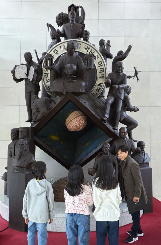 소중 학생기자단이 유다니엘(오른쪽) 대외협력센터 연구조원에게 뇌 연구에 영향을 끼친 인물들 조각상에 대해 설명을 듣고 있다.
