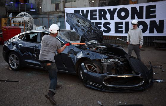 지난 4월 10일 영국 런던 남부 브릭스턴 소재 창장공간 '하데스 스튜디오'에서 열린 반(反) 일론머스크 시위에서 시위자들이 테슬라 차량을 부수고 있다. 연합뉴스·AFP