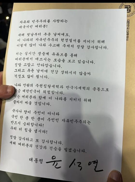 윤 전 대통령은 지난 1월 1일 서울 용산구 한남동 대통령 관저 앞에서 철야집회를 하는 지지자들에게 직접 서명한 새해 인사 및 감사 인사글을 전했다. [뉴시스]