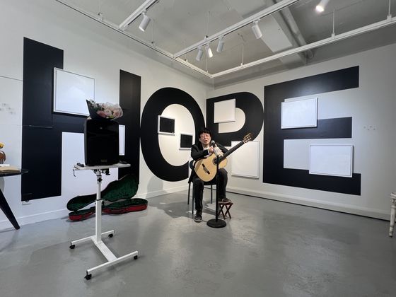 전시장에서 아트토크 중인 김창완. HOPE라고 쓴 벽면 위 그림들이 최신작이다.