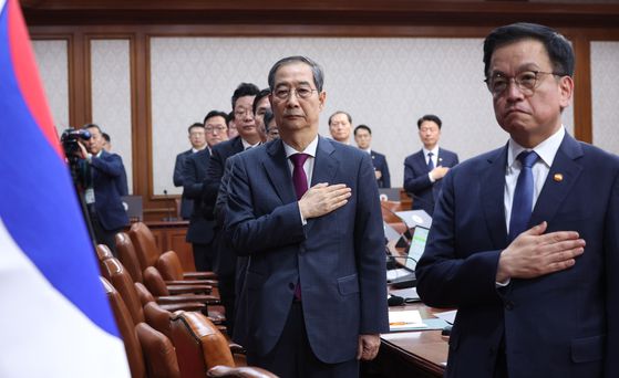 한덕수 대통령 권한대행 국무총리가 지난 14일 국무회의에서 국기를 향해 경례하고 있다. 오른쪽은 최상목 경제부총리 겸 기획재정부 장관. 최 부총리는 관세 관련 한미 양자 회담을 위해 22일 출국한다. 뉴시스