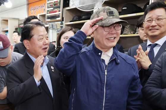 더불어민주당 이재명 대선 후보가 2일 강원도 화천군 한 군장점에서 김병주 최고위원이 사준 병장 계급장이 달린 육군 모자를 써보고 있다. 연합뉴스