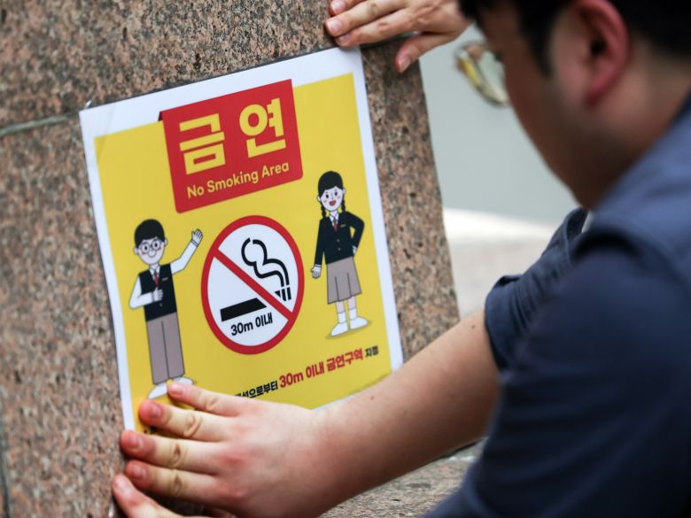지난해 서울의 한 빌딩 흡연구역에서 관계자가 '금연구역 지정 안내문'을 붙이고 있다. 뉴스1