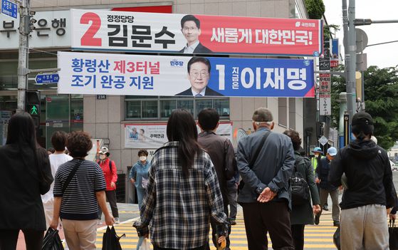 제21대 대통령 선거를 앞두고 19일 부산 남구 한 도로변에서 유권자들이 각 당의 대선 후보자를 알리는 현수막을 살펴보고 있다. 송봉근 기자