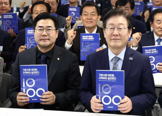 이재명 더불어민주당 대선 후보가 당대표이던 지난해 11월 13일 서울 여의도 민주당사에서 열린 2024 더불어민주당 기초자치단체장 교육연수에서 지방정부 기본사회 정책 사례가 담긴 책을 들고 기념촬영을 하고 있다. 왼쪽은 박찬대 당대표 직무대행 겸 원내대표. 뉴스1