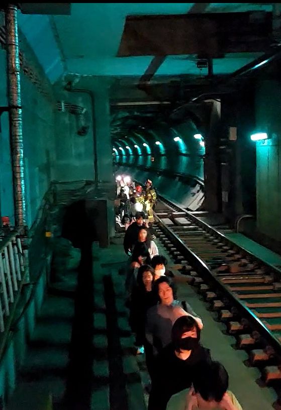 지난달 31일 오전 서울 지하철 5호선 마포역~여의나루역 구간을 지나던 열차 내부에서 방화로 인한 화재가 발생하자 승객들이 지하 터널을 따라 대피하고 있다. [뉴스1]