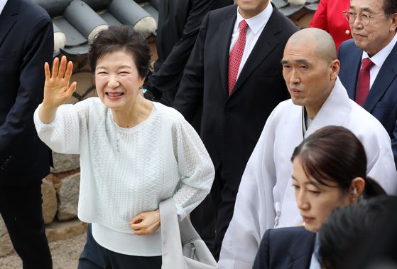 박근혜 전 대통령이 2일 부산 금정구 범어사를 방문해 주지 정오스님과 대웅전으로 향하며 지지자들에게 인사하고 있다. 뉴스1