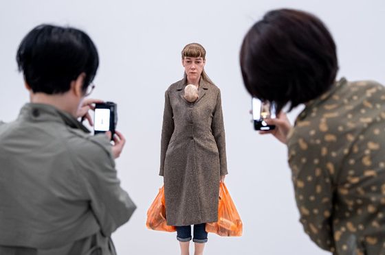 '소핑하는 여인'(2013) 앞의 관람객들. 영국에서 살고 있는 작가는 이곳 수퍼마켓 체인인 세인즈베리의 오랜지색 비닐백을 실제보다 작은 크기로 매 전시 때마다 만들어 보낸다. 한쪽에는 파스타와 소스 등 가족의 식량, 다른 쪽에는 기저귀와 베이비 파우더, 이유식 등 아기를 위한 것들이 들어 있다. 단 하나도 이 여성 자신을 위한 건 없다. 사진 국립현대미술관