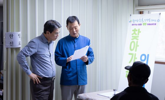 지난달 24일 김돈곤 청양군수(왼쪽)가 '찾아가는 의료원'이 마련된 청남면 내직1리 마을회관을 찾아 김상경 청양의료원장으로부터 진료 내용을 듣고 있다. [사진 청양군]