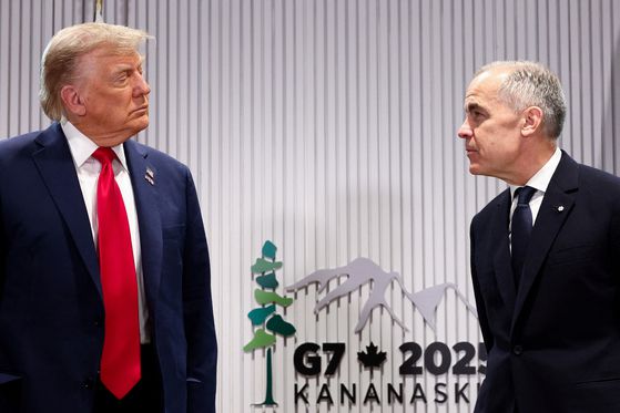 키어 스타머 영국 총리가 16일(현지시간) 캐나다 앨버타주 카나나스키스에서 열린 G7 정상회의에서 도널드 트럼프 미국 대통령과 무역협정에 서명한 뒤 기자들과 만난 자리에서, 트럼프 대통령이 떨어뜨린 협정문 서류를 급하게 집어들고 있다. 로이터=연합뉴스