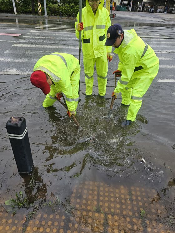 21일 광주 광산구 일대 도로 일부가 침수돼 구청 관계자가 안전 조치하고 있다. 사진 광주광산구