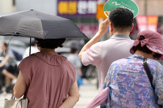 폭염이 일주일 넘게 이어진 4일 오후 대구 수성구 달구벌대로에서 시민들이 양산과 부채로 뙤약볕을 가리고 있다. 뉴스1