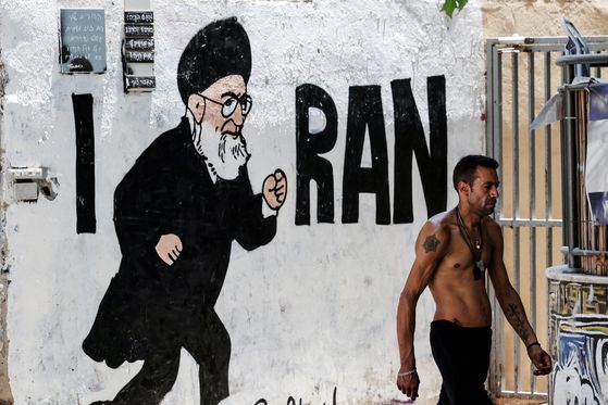 이스라엘 정부가 자국과 미국의 지난달 이란 핵시설 공격 이후에도 이란이 핵무기 원료가 될 수 있는 농축우라늄 비축분 일부를 여전히 보유하고 있다는 결론을 내렸다. 8일 이스라엘 텔아비브에서 한 남성이 이란 최고 지도자 아야톨라 알리 하메네이의 그림이 그려진 벽 옆을 걷고 있다. 로이터=연합뉴스