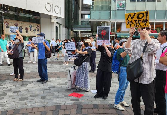 지난 17일 도쿄에서 참정당 후보자 유세장 뒤에 일부 시민들이 반대하는 피켓을 들고 있다. 오누키 도모코 특파원