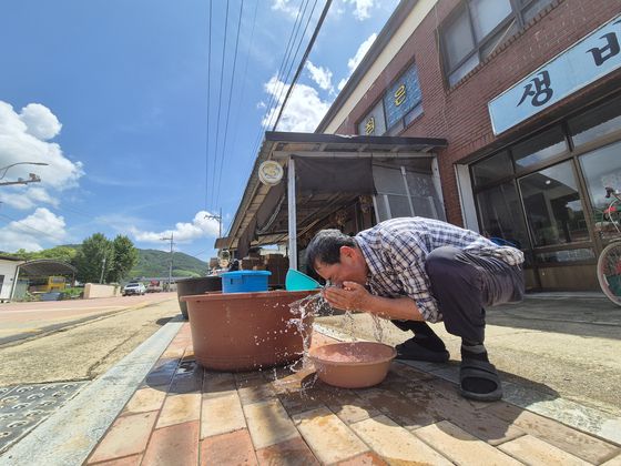 지난 21일 경남 산청군 신안면의 한 식당에서 식당 관계자가 공급받은 물로 흙탕물이 묻은 창문을 씻고 있다.   식당 관계자는 "호우 여파로 단전, 단수, 가스 공급이 중단됐고, 선풍기 돌릴 전기를 위층에서 끌어다가 쓰는 중이다"고 설명했다. 연합뉴스