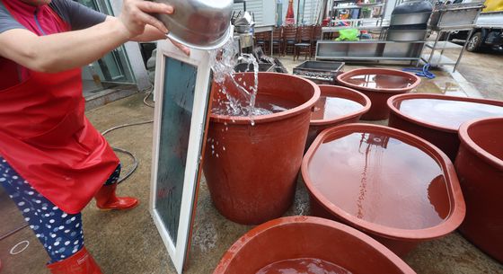 22일 오전 경남 산청군 신안면 야정마을 한 비닐하우스에서 호우 피해 주민들이 농업용 지하수 관정에서 끌어올린 물로 진흙 범벅이 된 옷가지와 옷걸이를 세척하고 있다. 단수로 가정에 물이 나오지 않아서다. 안대훈 기자