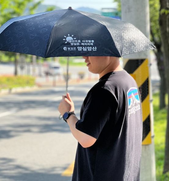 대구 달성군에서 한 시민이 뜨거운 햇살을 막기 위해 양심양산을 대여해 쓰고 있다. [대구 달성군]