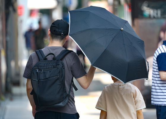 전국 대부분 지역에 폭염 특보가 이어진 지난 9일 대구 중구 동성로에서 한 시민이 자녀에게 양산을 씌워주며 이동하고 있다. 뉴스1