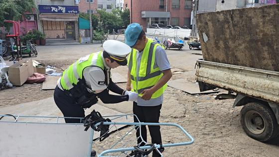 지난달 26일 서울 강동경찰서 소속 경찰관이 관내 철물점에서 폐지 수집인에게 형광 조끼를 입혀주고 있다. 사진 서울 강동경찰서