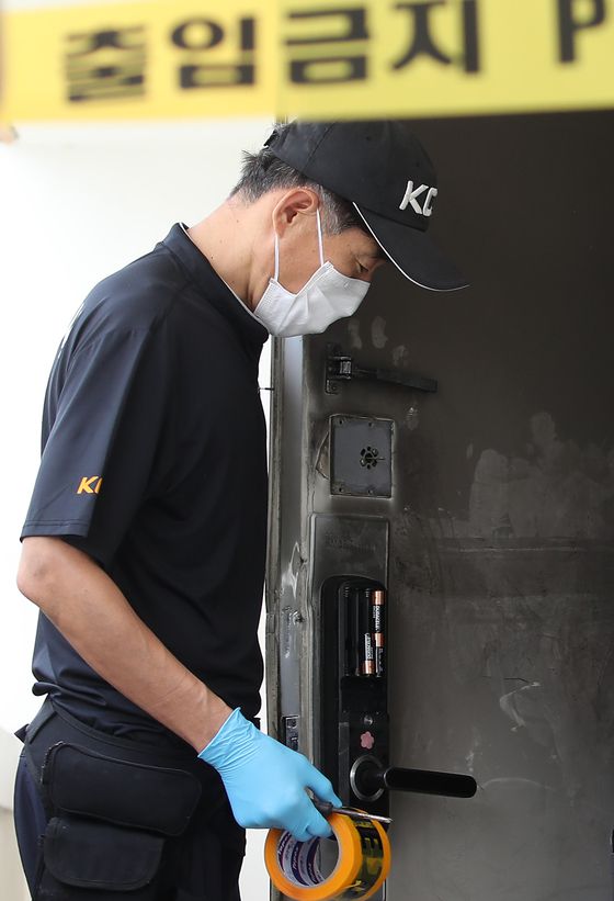 지난 10일 오후 경찰이 아파트 주변을 통제한 뒤 현장감식을 진행하고 있다. 불이 난 아파트 현관 출입문 잠금장치(도어락)에 건전지 일부가 빠져 있다. 뉴스1