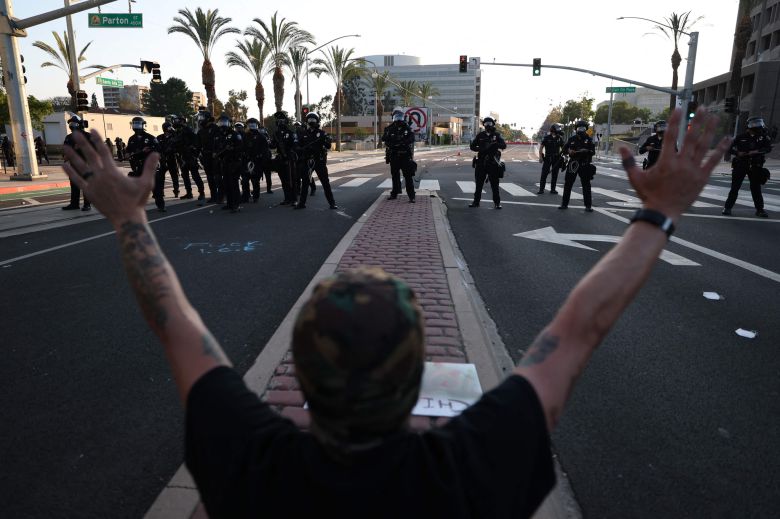 지난 6월 9일(현지시간) 미국 캘리포니아주 산타아나에서 이민·관세 집행국(ICE)의 급습 소식이 전해진 후, 한 시민이 미국 시민권·이민 서비스국(USCIS) 산타아나 지역 사무소 밖에서 경찰 대열을 향해 손을 들어 올리고 있다. AFP=연합뉴스