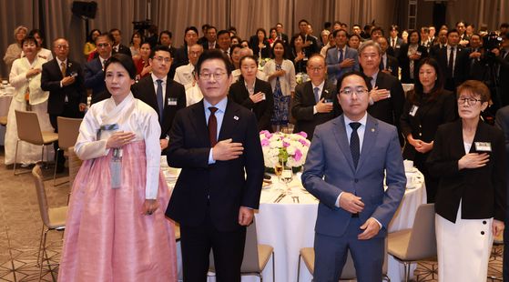 이재명 대통령과 김혜경 여사가 24일(현지시간) 미국 워싱턴DC의 한 호텔에서 열린 동포 만찬 간담회에서 국기에 경례하고 있다. 이 대통령 오른쪽은 앤디 김 미국 상원의원. 연합뉴스