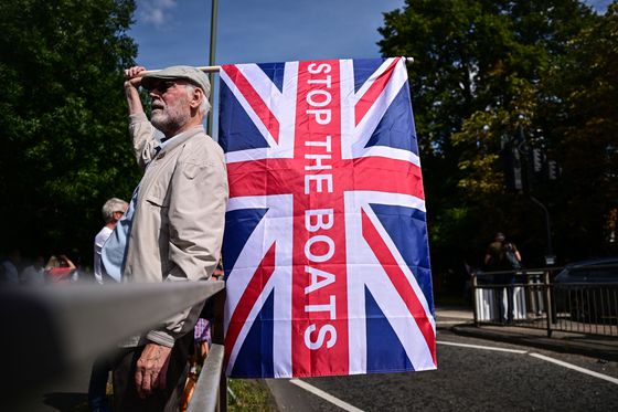 지난달 23일(현지시간) 영국 런던 남쪽 호를리에 있는 난민 수용 시설로 추정되는 쉐라톤 포 포인츠 호텔 밖에서 열린 반이민 시위에서 한 시민이 '배를 멈춰라(Stop The Boats)'라고 쓰인 영국 국기를 들고 있다. AFP=연합뉴스