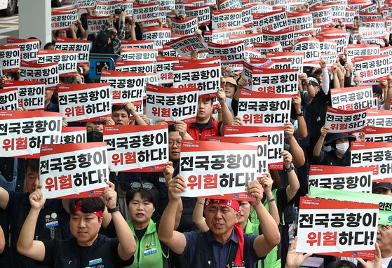 인천국제공항 노동자가 가입한 민주노총 공공운수노조 인천공항지역지부와 나머지 14개 공항 노동자가 가입한 전국공항노동조합으로 구성된 전국공항노동자연대가 지난달 19일 인천 영종도 인천국제공항 제2여객터미널에서 연 총파업 대회에서 참가자들이 손팻말을 들고 구호를 외치고 있다. 연합뉴스