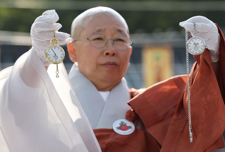 진관사 주지 법해스님이 25일 김진 광복회 부회장에게 받은 김구 선생과 윤봉길 의사가 교환했던 회중시계 복각을 들어보이고 있다. 김경록 기자