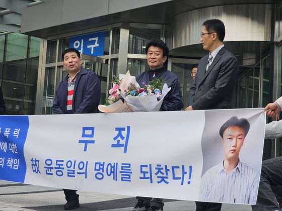 이춘재 연쇄살인 용의자로 몰렸던 고(故)윤동일씨의 친형(오른쪽에서 두번째)이 30일 재심 재판 선고 직후 법원 앞에서 기자회견을 하고 있다. 이날 재판에는 이춘재 8차 사건 용의자로 몰려 억울하게 옥살이를 한 윤성여씨(왼쪽)도 방청했다. 최모란 기자