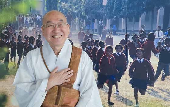 법륜 스님이 국제구호활동 차원에서 교육을 지원하고 있는 인도 학교의 학생들 사진 앞에 서 있다. 권혁재 사진전문기자