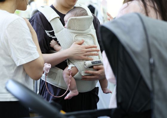 지난 8월 서울 코엑스에서 열린 베이비페어에서 관람객들이 아기띠를 체험해보고 있다. 뉴시스