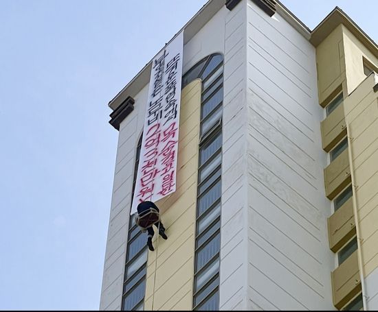 10일 전남 나주시 빛가람동 한 고층 아파트에서 해당 아파트 도장 업체 관계자 A씨가 현수막을 내걸고 고공농성을 벌이고 있다. 연합뉴스