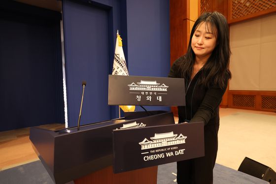 대통령실 직원이 21일 청와대 춘추관에서 대브리핑룸에서 단상에 부착할 청와대 업무표장을 점검하고 있다. [대통령실 사진기자단]