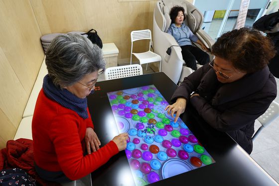 지난 18일 서울마음편의점 동대문점에서 한 주민이 안마의자에서 휴식을 즐기고 있다. 주민 2명은 자가진단 테스트나 치매 예방 게임 등이 가능한 '해피 테이블'에서 게임 중이다. 김종호 기자