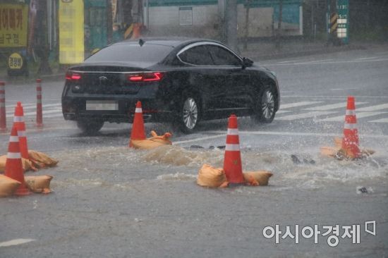 광주지역에 호우특보가 발효된 7일 오후 3시께 광주광역시 서구 화정동 한 도로 배수구가 파손돼 빗물이 역류하면서 도로 일대가 통제됐다.