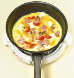 4. 달걀물은 넓게 펴고 치즈를 얹고 볶은 양송이버섯과 햄, 토마토, 파프리카를 얹은 다음 접어서 오믈렛을 만든다.