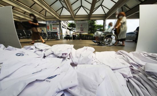 전국의사 2차 총파업 첫날인 26일 오후 경기도 수원시 아주대학교병원에서 의료진이 벗어놓은 가운 앞으로 병원을 방문한 시민들이 지나고 있다. [이미지출처=연합뉴스]