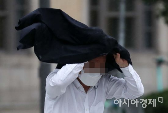 제8호 태풍 '바비'의 영향으로 비가 내린 27일 서울 광화문 사거리에서 한 시민이 외투로 비를 피하고 있다. /문호남 기자 munonam@