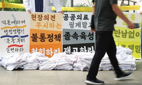 전국의사 2차 총파업 첫날인 26일 오후 경기도 수원시 아주대학교병원에서 의료진이 벗어놓은 가운 뒤에서 피켓 시위를 하고 있다. [이미지출처=연합뉴스]