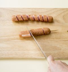 2. 소시지를 돌려가며 칼로 회오리 모양을 그리며 칼집을 낸 다.