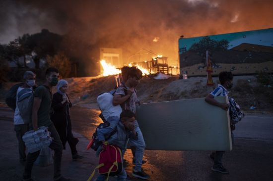 9일(현지시간) 난민들이 화재를 피해 모리아 수용소에서 빠져나오고 있다. [이미지출처=AP연합뉴스]
