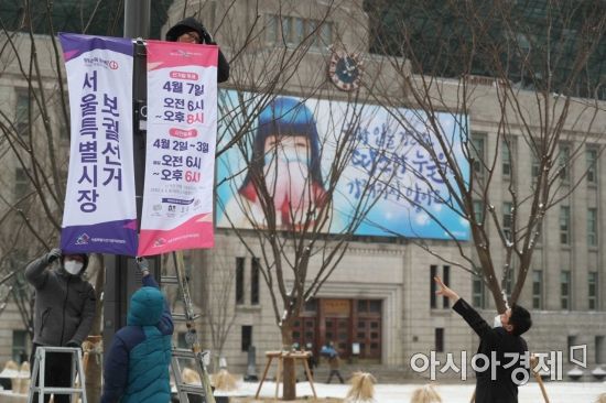 서울·부산 시장 보궐선거가 50일 앞으로 다가온 16일 서울시선거관리위원회 관계자들이 시청 인근 도로변에서 선거일을 알리고 유권자의 투표 참여를 독려하기 위해 가로등 현수기를 설치하고 있다. /문호남 기자 munonam@