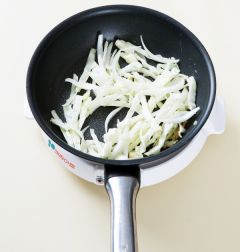 2. 팬에 식용유를 두르고 다진 마늘을 넣어 볶다가 양배추와 양파를 넣어 센 불에 2분 정도 볶는다.