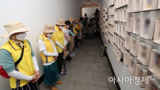 세월호 유족들이 학생 등 참사 희생자들의 사진이 가지런히 걸린 벽 앞에서 묵념을 하고 있다. /문호남 기자 munonam@