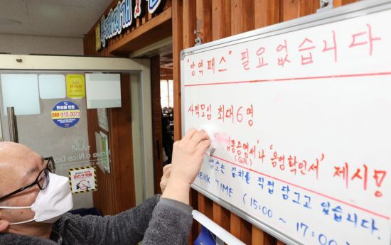 서울 종로구 한 식당에서 관계자가 기존 방역패스 안내문을 수정하고 있다. [이미지출처=연합뉴스]