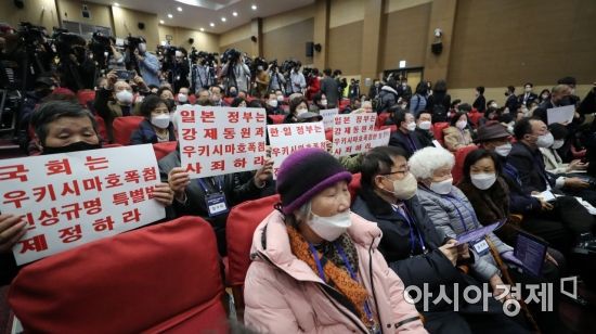 12일 국회에서 열린 강제징용 해법 논의를 위한 공개토론회에 참석한 참가자들이 피켓을 들고 있다./윤동주 기자 doso7@
