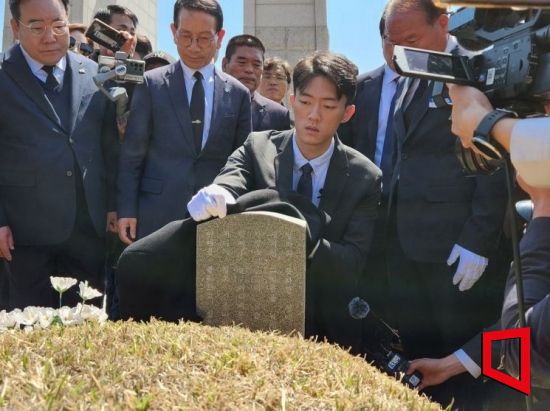 전우원씨가 고(故) 김경철 열사의 묘역의 먼지를 겉옷으로 닦고 있다.[사진=민현기 기자]