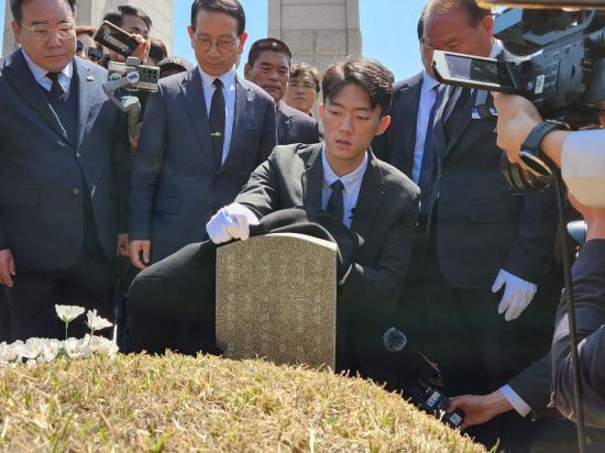 전우원씨가 고(故) 김경철 열사의 묘역의 먼지를 겉옷으로 닦고 있다.[사진=민현기 기자]